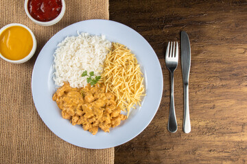 Food dish with chicken stroganoff and rice and chips.