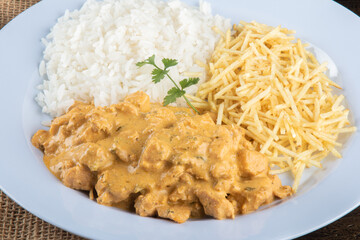Food dish with chicken stroganoff and rice and chips.