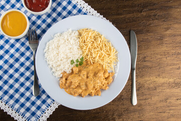 Food dish with chicken stroganoff and rice and chips.