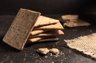 Dry crackers with flax and sesame seeds on a dark background. Advertising, poster.