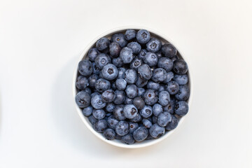 Top view of fresh ripe blueberries in bowl on white background
