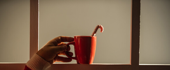 merry christmas. happy new year. red cup with milk and candy stick. hot cocoa for santa claus. xmas mood and meal. food and drinks. enjoy tasty beverage. warm tea for you. man hand hold cup - Powered by Adobe