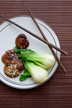 Overhead view of braised Chinese mushrooms and baby bok choy served on plate
