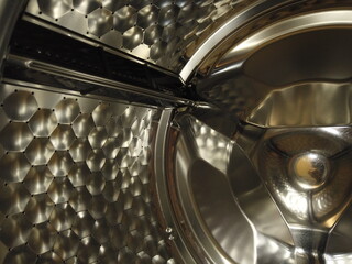 Inside the Laundromat is shiny drum. Brum of professional washing machine, closeup.