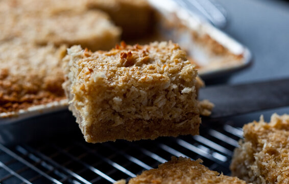 Close up of slice of sesame coconut bars on cooling rack