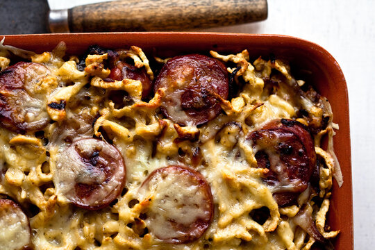Overhead view of spaetzle with smoked kielbasa and caramelized onions served in tray