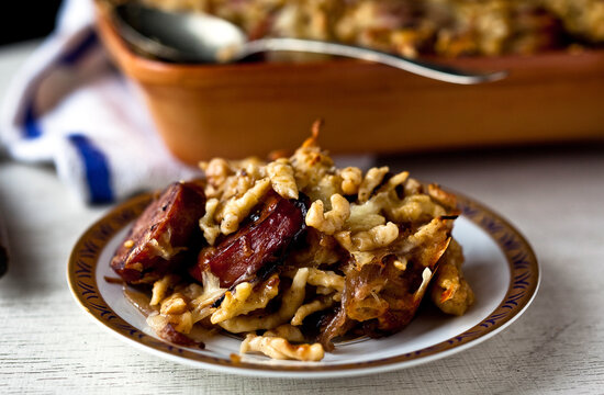 Close up of spaetzle with smoked kielbasa and caramelized onions served on plate