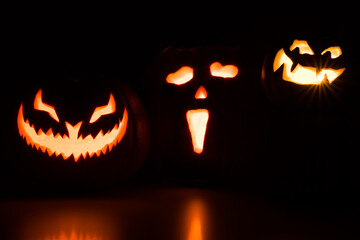 Three carved pumpkins glowing in the dark