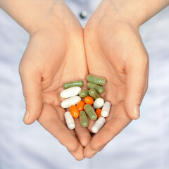 woman in white coat holding a handful of pills in palms