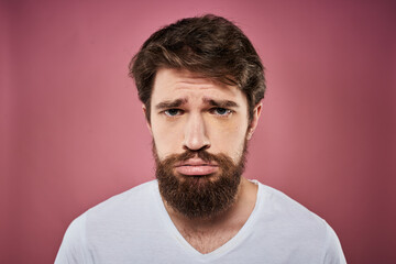 Obraz premium Emotional bearded man in white T-shirt discontent pink background