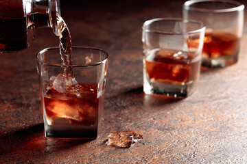 Pouring whiskey in glass with natural ice.
