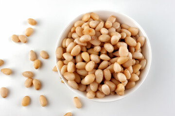 Pine nut in ceramic bowl on white background, top view