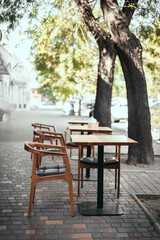 Fototapeta na wymiar Coronavirus crisis. Outdoor empty street restaurant with wood style chairs on a sunny summer day