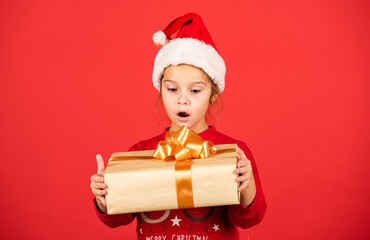 Unbelievable. Amazing surprise. Merry Christmas and happy holidays. Winter holidays. Xmas gift shopping. Gift package. Small adorable girl Santa hat hold gift box. Kid hold present box red background