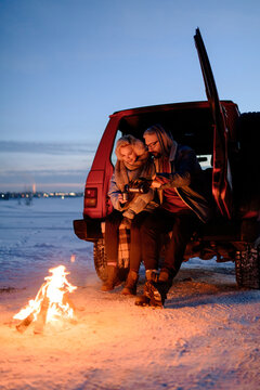 Young couple sharing drink near bonfire