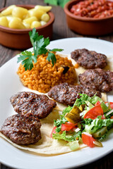 Kofte (kefte) - Turkish cutlets (meat balls) made from lamb and beef meat and spices, cooked over charcoal. Served on a platter with salad and bulgur. Close-up