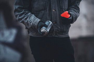 Man in denim jacket uses red fluorescent spray paint. Process making graffiti.