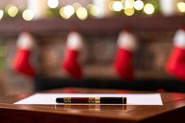 Fountain pen, sheet of  on the table on background of christmas fireplace with decoration of light bulbs. Concept of writing wish list.