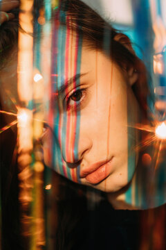 Melancholic young lady among colorful shining ribbons