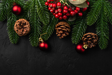 Christmas composition. red ornament, pine cones and fir needles decorations on dark background. Top view copy space