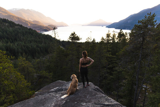 A fit female runner overlooking the BC Coast with her dog