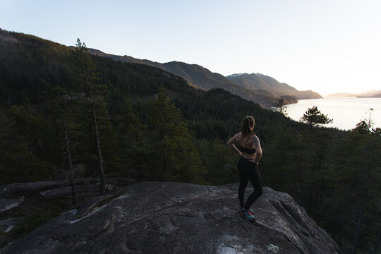 A fit female runner overlooking a forest on the BC Coast