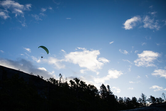 A silhouette of a paraglider taking off