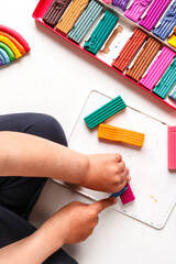 Toddler boy sculpting colored rainbow from children's play clay plasticine . Homework for families in quarantine social isolation in the coronavirus pandemic. Stay at home, home schooling flat lay