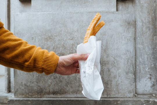 Anonymous person holding bread roll in package