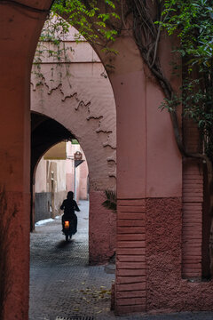 Motorcyclist retreating along narrow road under big arch