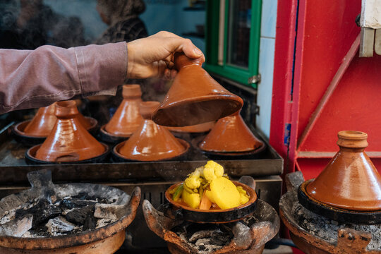 Male staff checking earthenware pot with warm meal