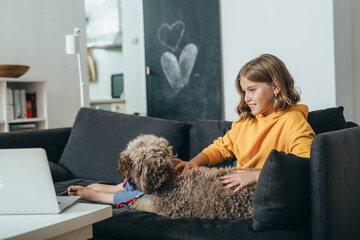 teenaged girl sitting on sofa with her dog at home