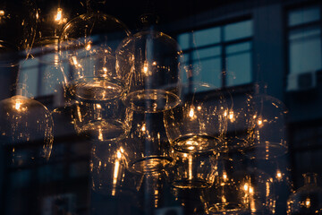 Unusual lamps in the interior of a cafe or restaurant, unusual use of large glasses hanging from the ceiling. Image through the showcase, selective focus