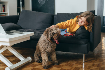 teenaged girl sitting on sofa with her dog at home