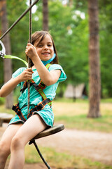 Little girl in mask and harness on the trail in the sky rope park