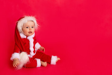 child on a red background in a Santa suit, the concept of new year and Christmas, place for text