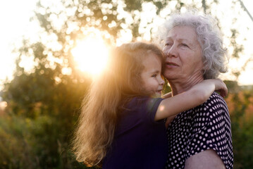 Portrait of a grandmother with her grandaughter on a sunset time.