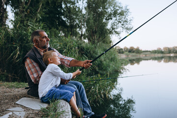 boy fishing with his grandfather by the lake