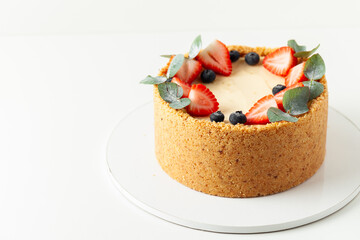 Homemade classic New York cheesecake with crunchy crust decorated with fresh strawberries and blueberries on the white background