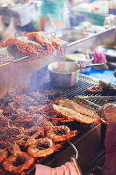 Faceless chef grilling crayfishes in outdoors market