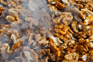 Walnut texture with steam close up. Many halves of peeled nuts. Food in blue smoke. Contrasting dramatic light.