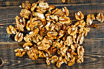 Walnut texture close up. Many halves of peeled nuts on an old wooden board. Food on a background of shabby brown board.