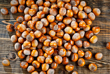 Hazelnuts on a pile close up. Texture of nuts on an old wooden board. Lots of nuts on a brown shabby table.