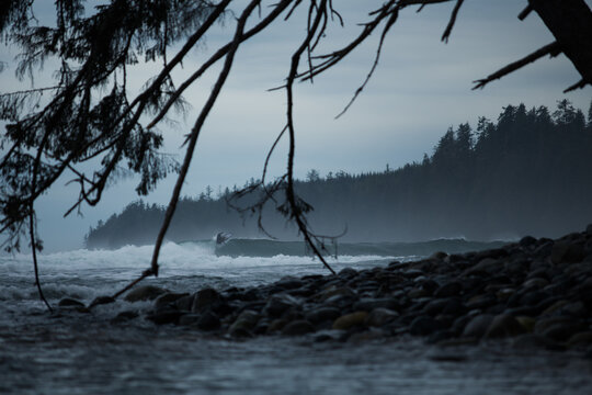 A surfer riding a wave on a stormy day on the BC coast