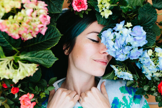 smiling woman surrounded by flowers.
