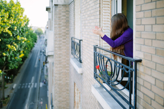Young woman clapping for healthcare workers in Paris during the Covid-19 lockdown