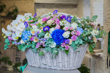 Large floral basket with colorful flowers at workshop, flower shop. Floristry, holiday, romantic, celebration, handmade and small business concept