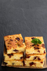 Homemade cottage cheese casserole slices on black stone background