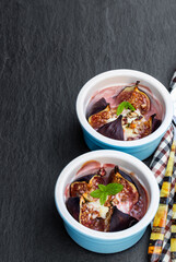 Baked fig with goat cheese and walnuts with honey on black stone background