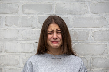 Emotional portrait of a girl crying and hiding her face isolated on black with space for text